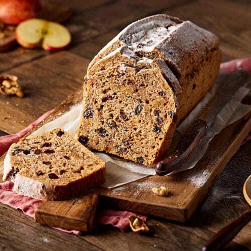 Saftiges Apfelbrot mit Nüssen, aufgeschnitten auf einem Holzbrett.