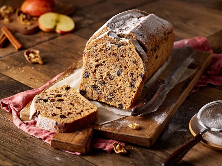 Saftiges Apfelbrot mit Nüssen, aufgeschnitten auf einem Holzbrett.