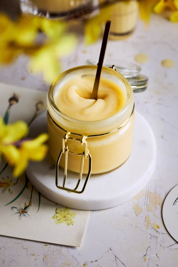 Cremige Eierlikörcreme im Glas mit goldenem Löffel, bereit zum Genießen.