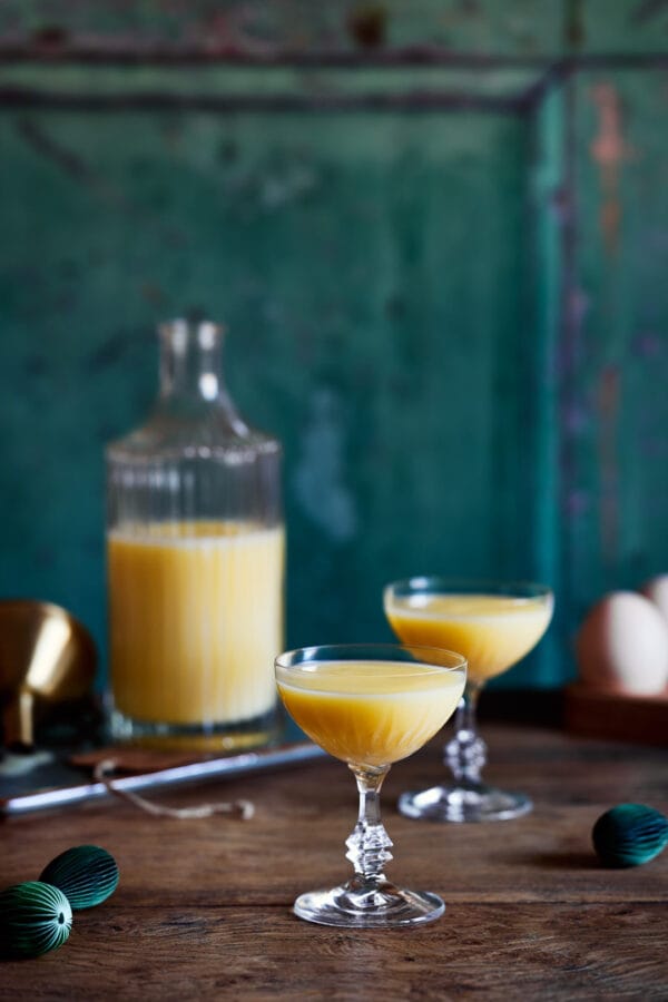 Cremiger Eierlikör in einem stilvollen Glas serviert, mit einer Flasche im Hintergrund.