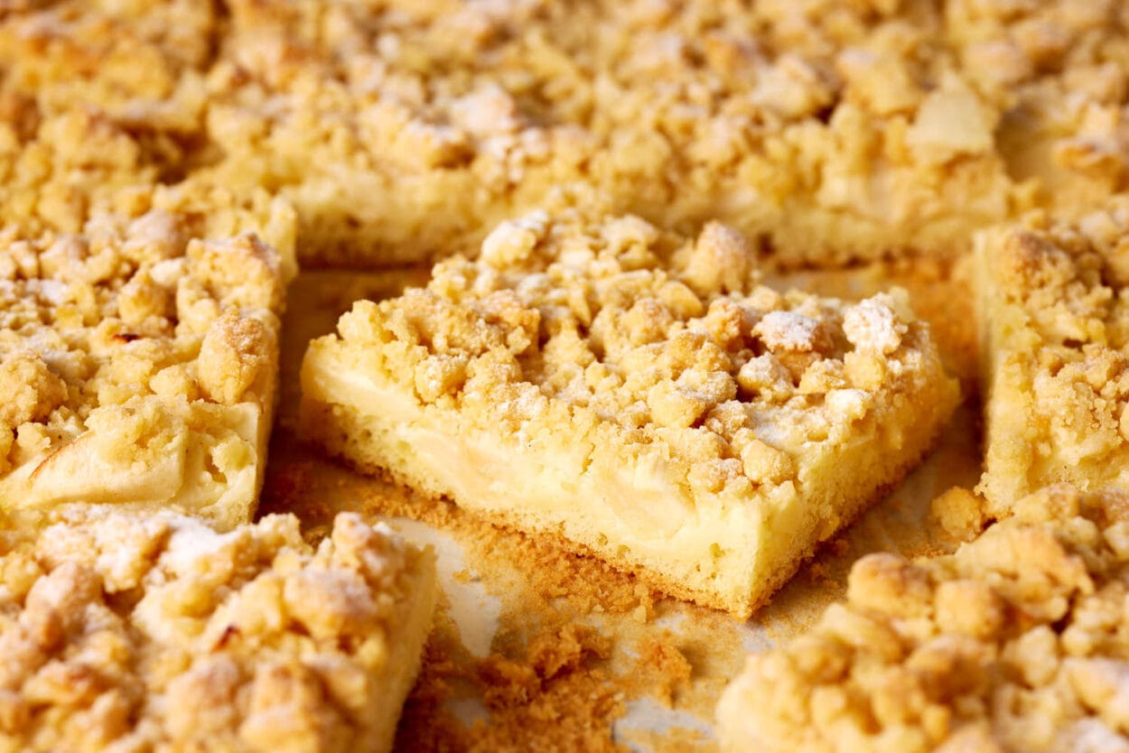 Apfelkuchen vom Blech mit Pudding und knusprigen Butterstreuseln – detailreiche Nahaufnahme eines Kuchenstücks.