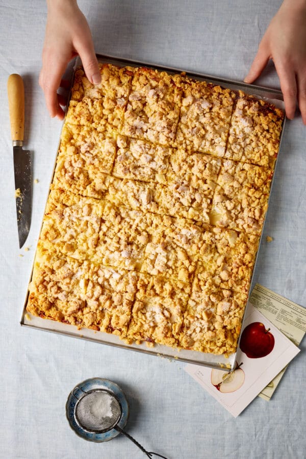 Frisch gebackener Apfelstreuselkuchen mit Pudding auf dem Blech – goldbraune Streusel auf cremiger Vanillepuddingschicht.