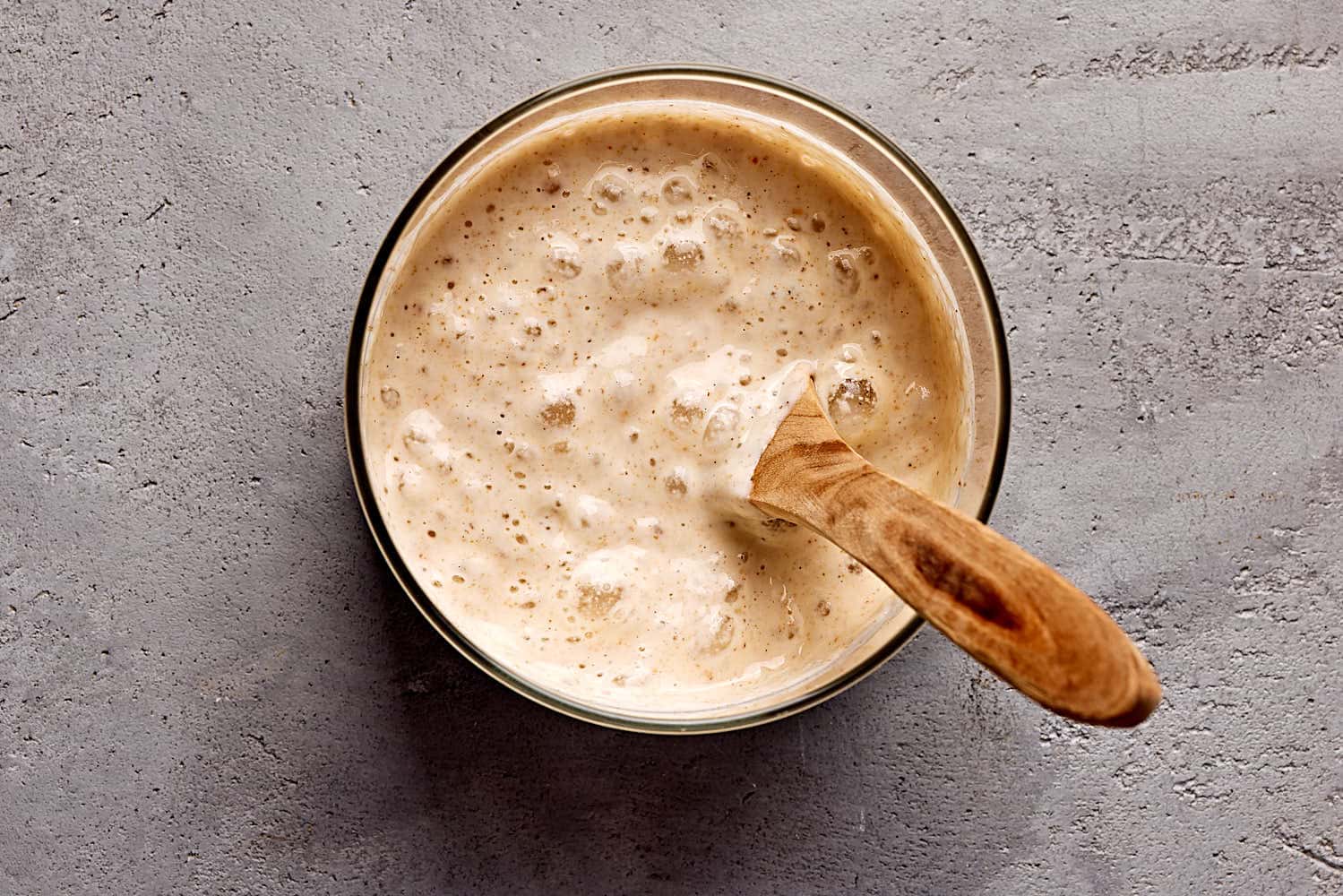 Reifer Weizensauerteig mit vielen Luftbläschen in einem Einmachglas.