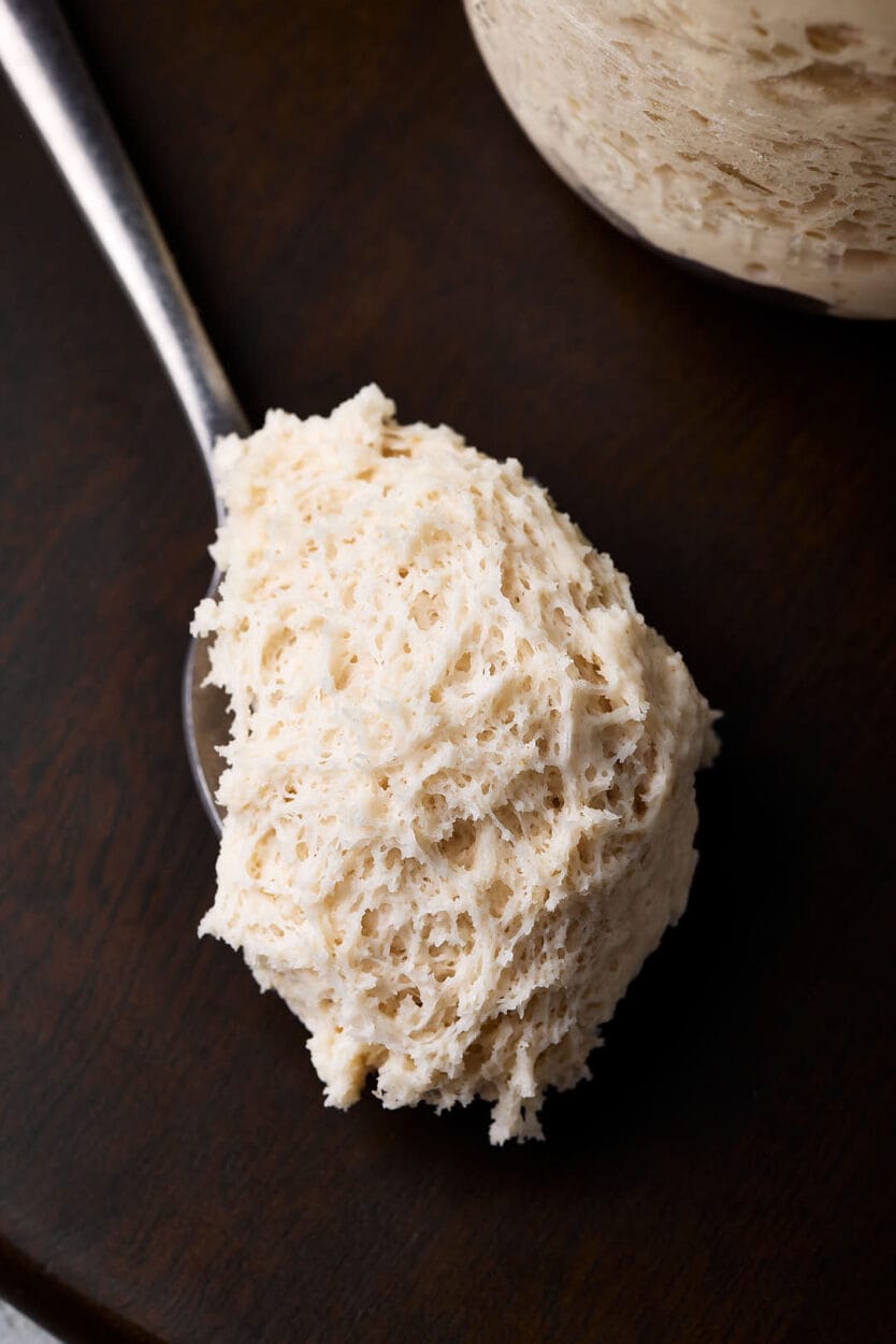 Nahaufnahme von Lievito Madre, italienischer fester Weizensauerteig auf einem Löffel mit gut sichtbaren Luftbläschen.