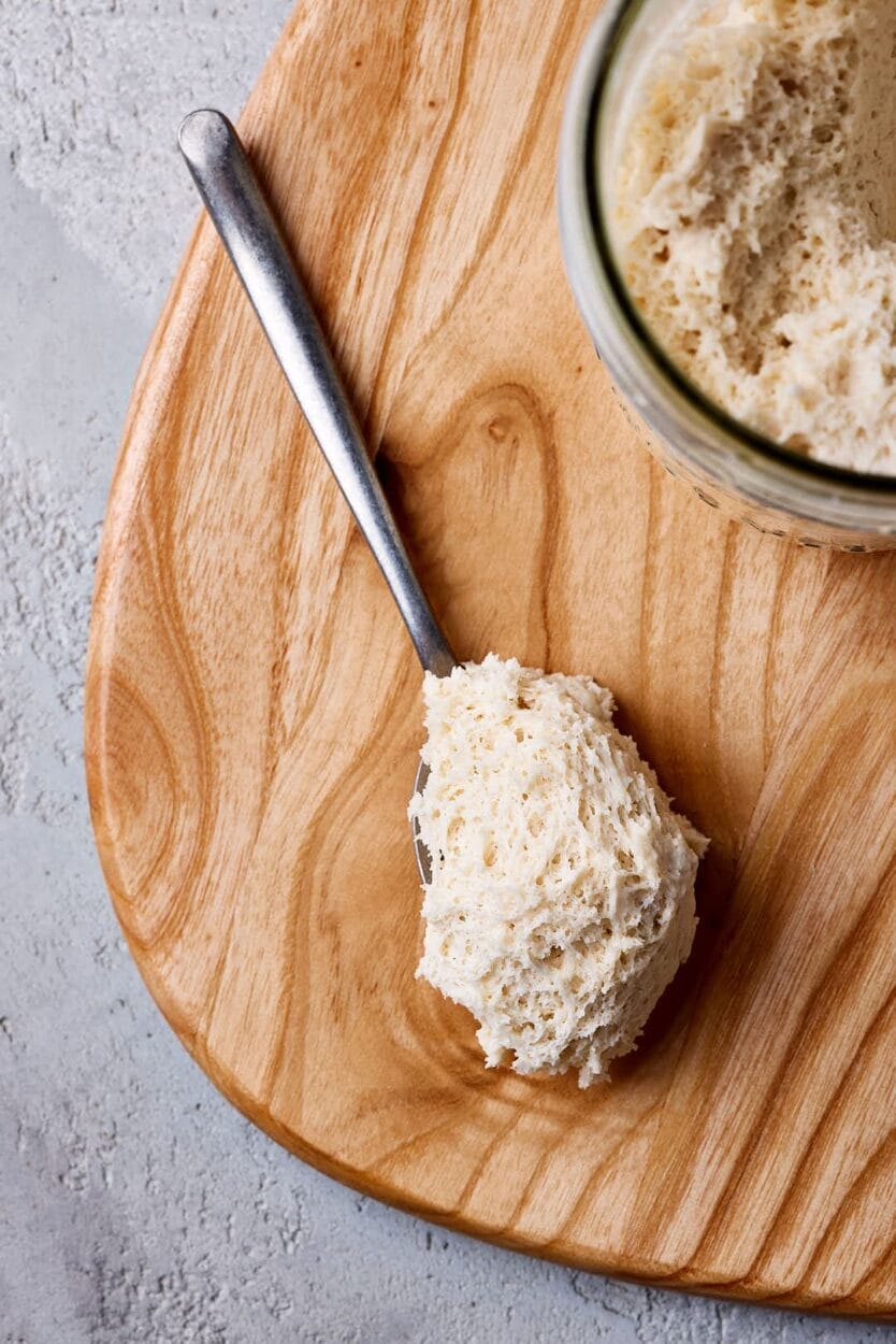 Lievito Madre, italienischer fester Weizensauerteig auf einem Löffel mit gut sichtbaren Luftbläschen.