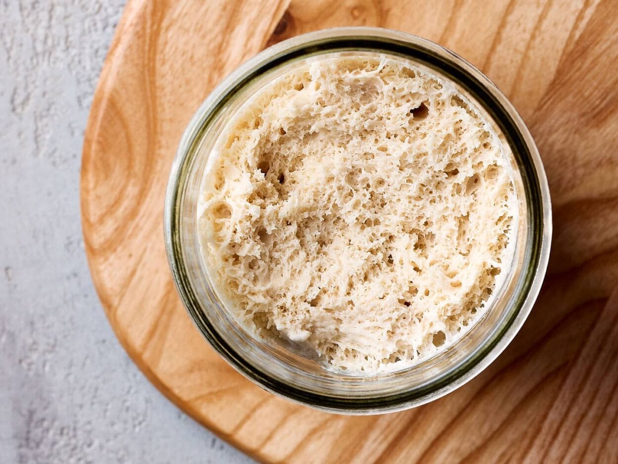 Nahaufnahme von Lievito Madre, italienischer fester Weizensauerteig auf einem Löffel mit gut sichtbaren Luftbläschen.
