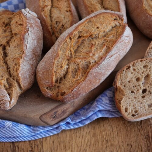Alpenkrusties - rustikale Brötchen mit Roggenmehl auf einem rustikalen Holzbrett.
