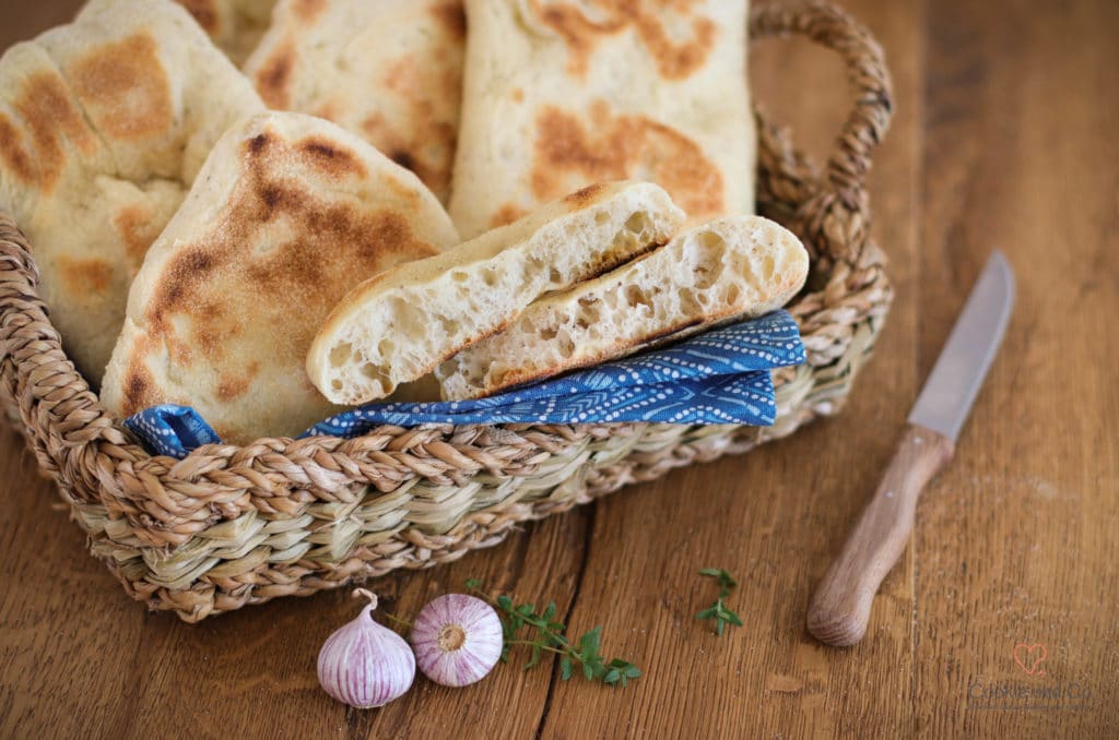 Grill-und Pfannenbrot in einem Brotkorb mit einem Messer und Knoblauchzehen daneben.