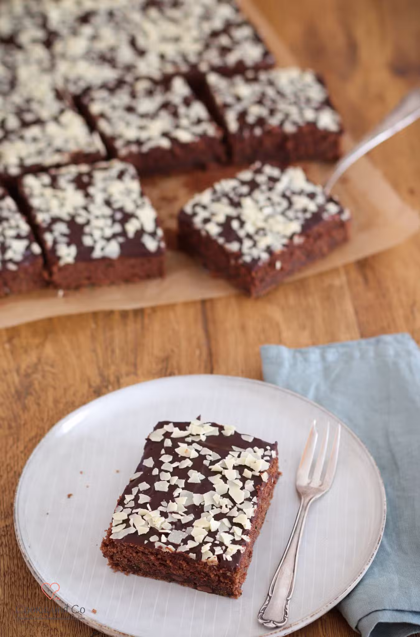 Saftiger Schoko-Zucchinikuchen mit Schokoglasur und weißen Schokoladenraspeln.