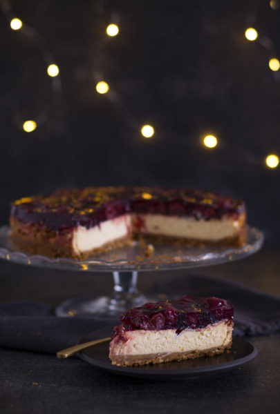 Christmas Cheesecake auf einer Tortenplatte und davor ein Kuchenstück auf einem Teller