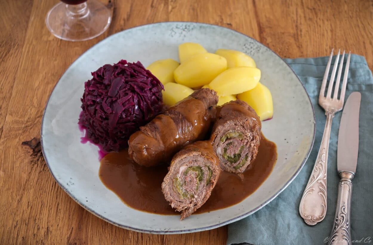 Klassische Rinderrouladen aus dem Ofen mit Soße, mit Rotkohl und Salzkartoffeln.