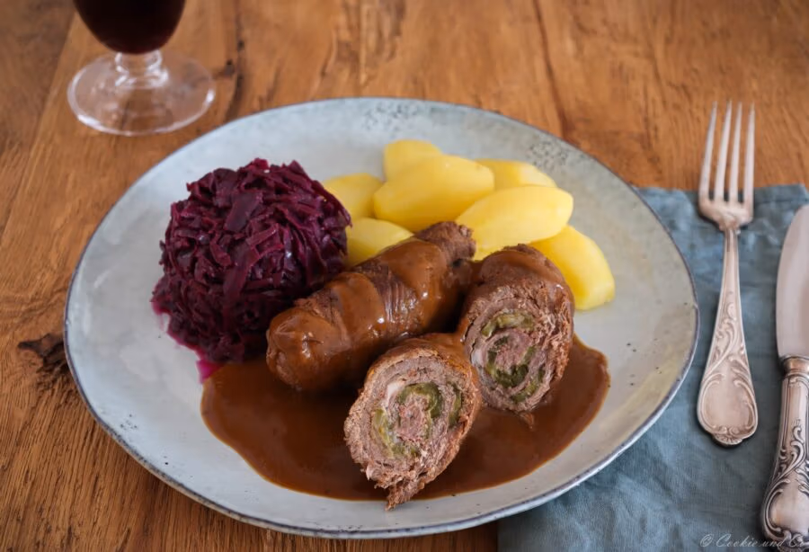 Klassische Rinderrouladen aus dem Ofen mit Soße, mit Rotkohl und Salzkartoffeln.