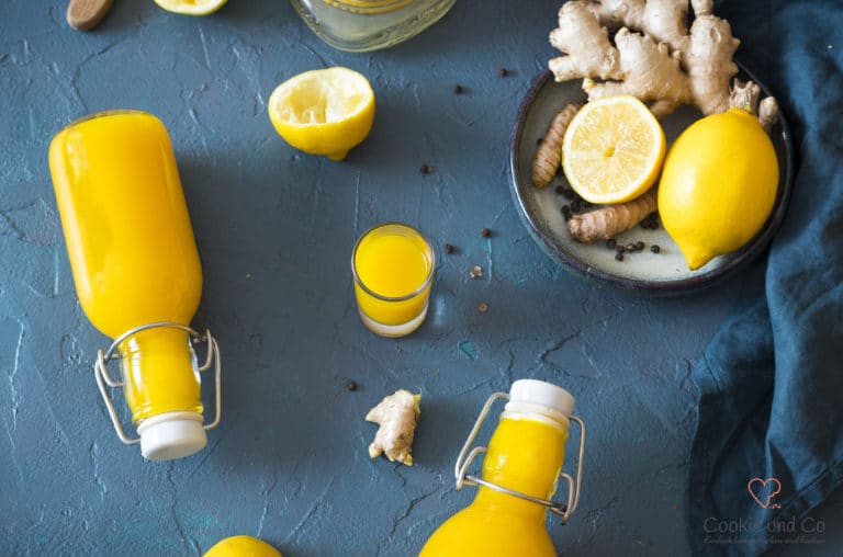 Zitronen-Ingwer-Trunk mit Kurkuma in einem Glas und Flaschen