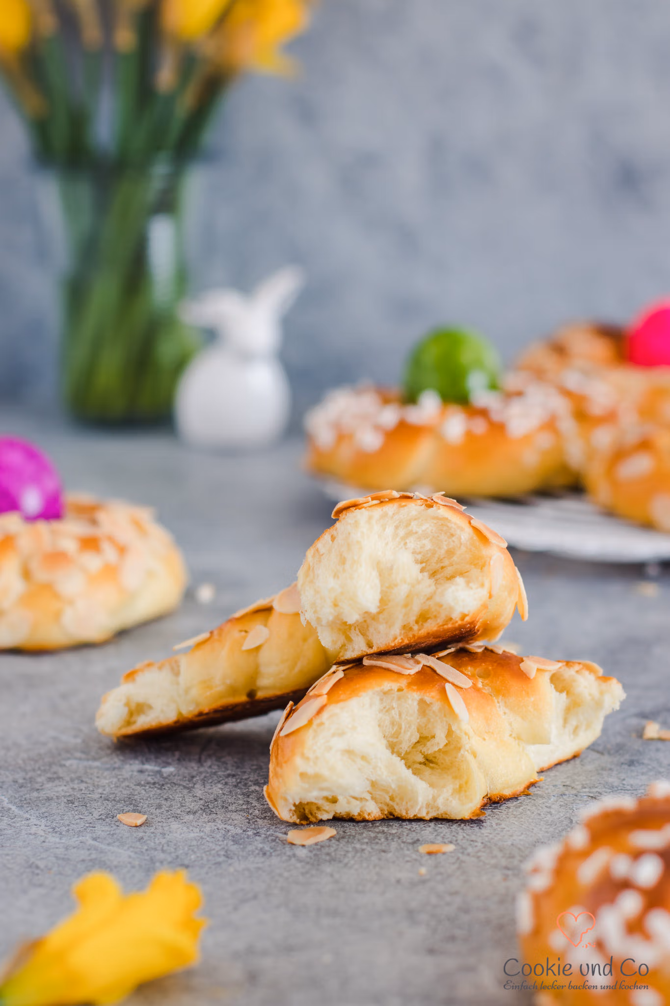Dinkel-Osterkränze mit gefärbten Eiern und Narzissen im Hintergrund.