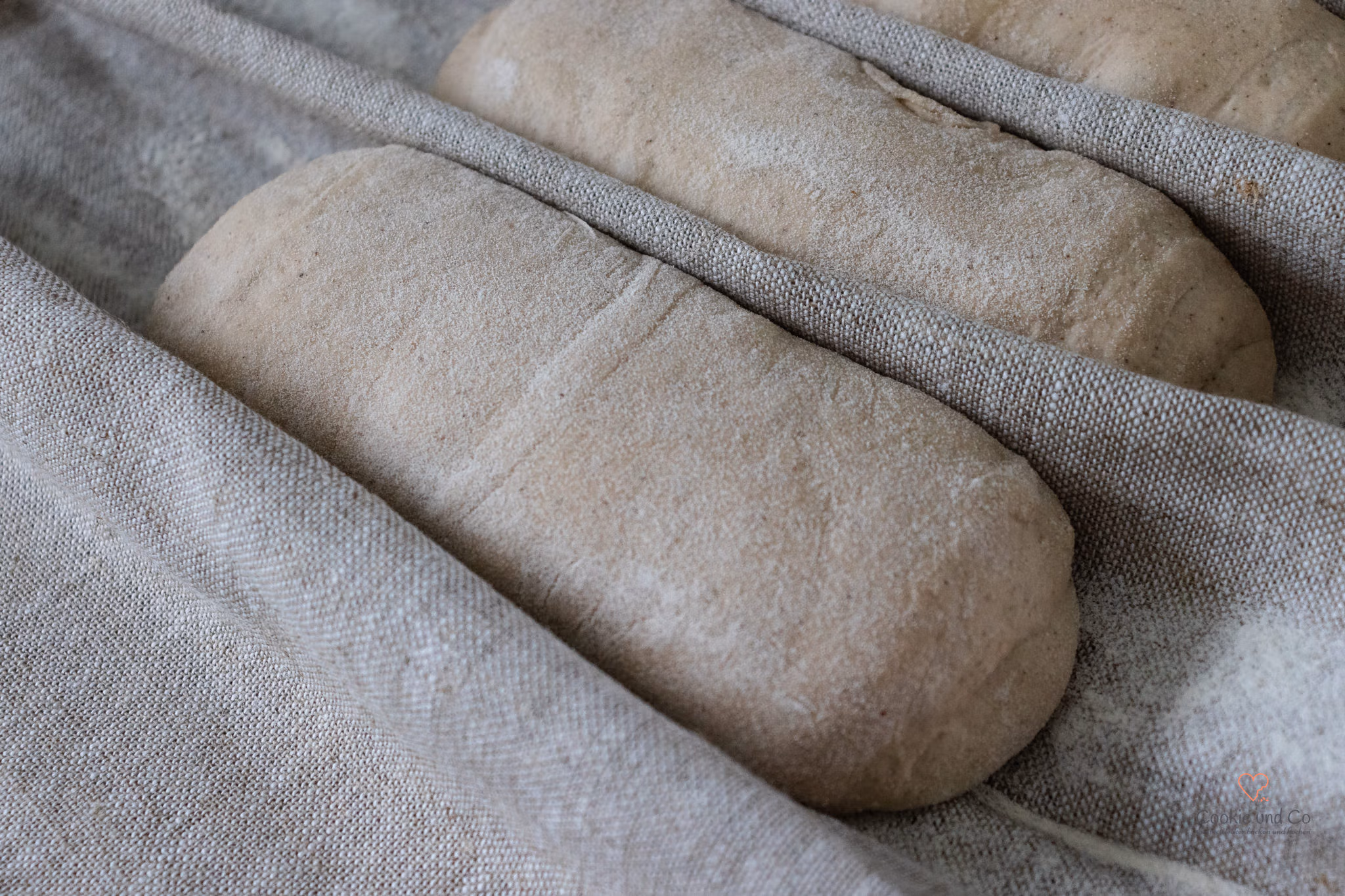 Vorgeformte Baguette-Teiglinge (Preshape) bei der Zwischengare im Bäckerleinen.