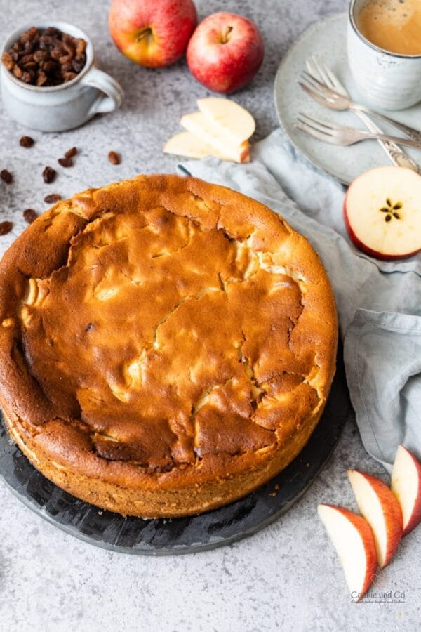 Saftiger Apfel-Quark-Kuchen mit Äpfeln und einer Tasse Kaffee im Hintergrund.