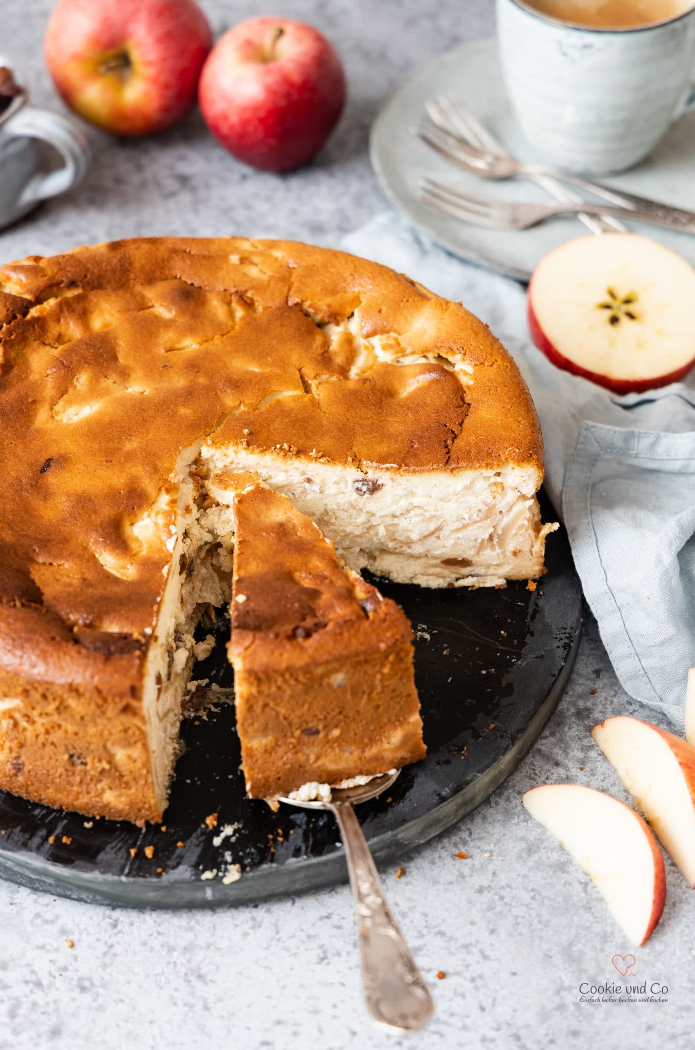 Saftiger Apfel-Grieß-Kuchen mit Äpfeln und einer Tasse Kaffee im Hintergrund.