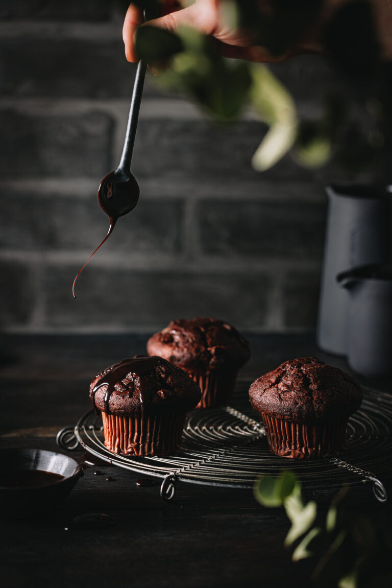 Schokoladenmuffins mit einer ausgepusteten Kerze auf einem Kuchengitter.