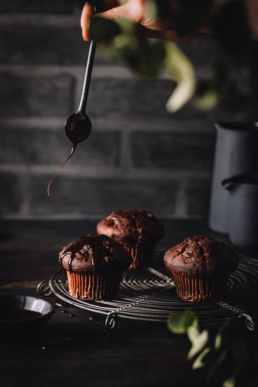 Schokoladenmuffins mit einer ausgepusteten Kerze auf einem Kuchengitter.