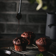 Schokoladenmuffins mit einer ausgepusteten Kerze auf einem Kuchengitter.