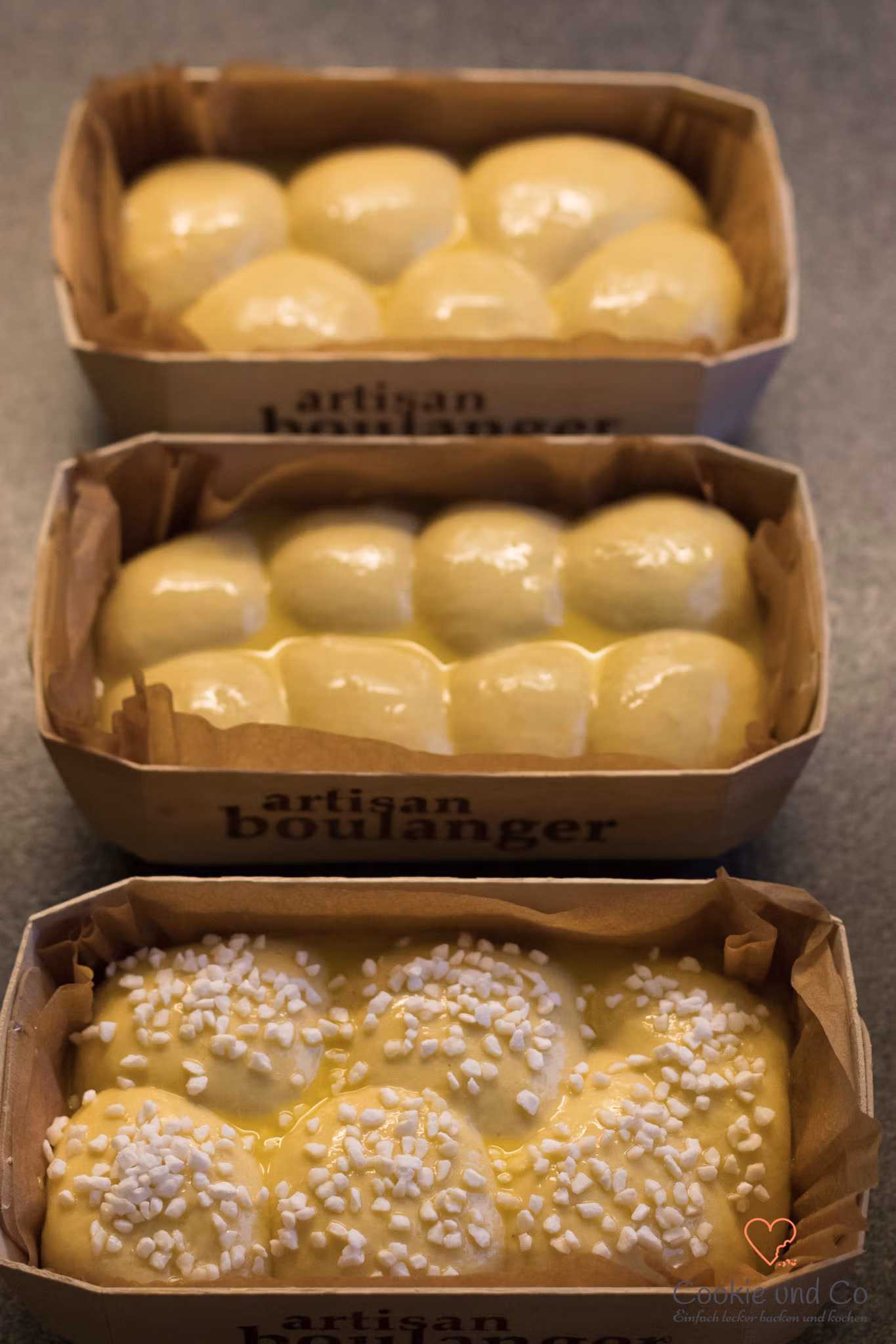 Dinkelbrioche in Holzbackförmchen mit Eistreiche bestrichen und Hagelzucker bestreut.