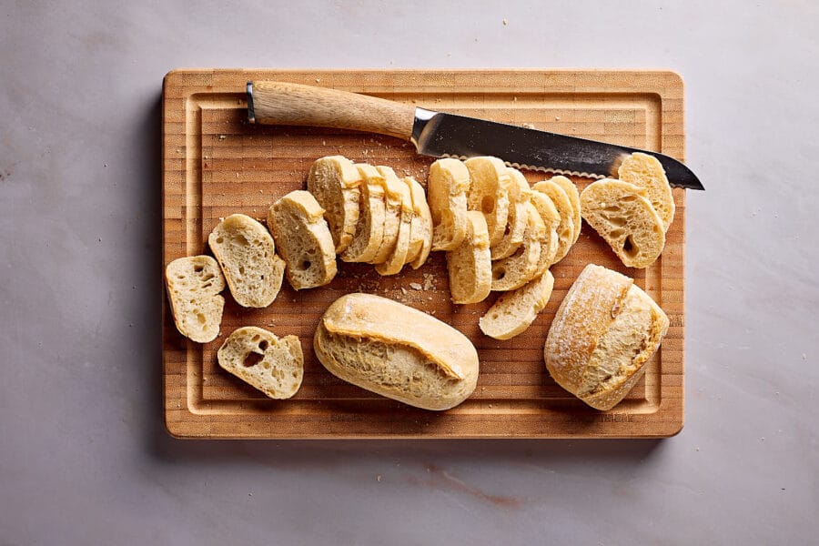 Altbackene Brötchen für Brotchips in Scheiben schneiden.