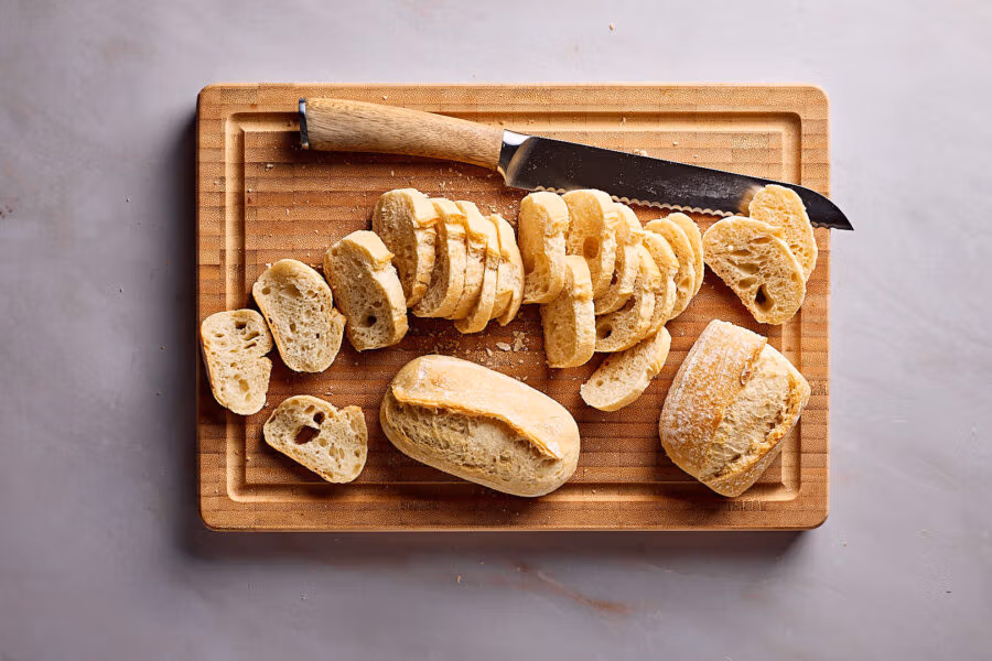 Altbackene Brötchen für Brotchips in Scheiben schneiden.