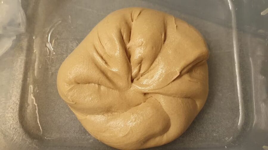 Fertig gekneteter Teig für eine Weizenvollkornkruste in einer geölten Teigwanne.