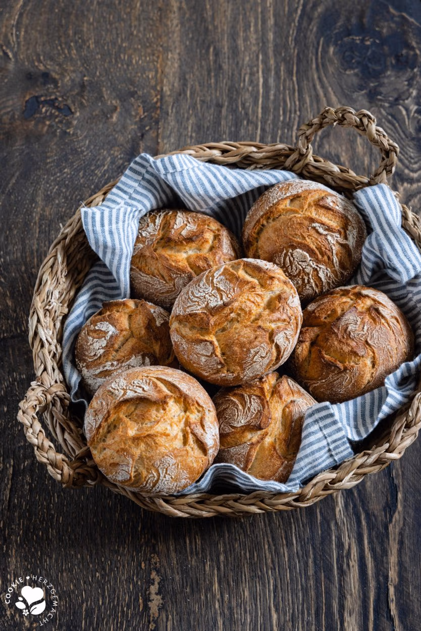 Rustikale Auffrischbrötchen mit Sauerteigresten in einem Brötchenkorb mit einem Blau gestreiften Tuch. Die Brötchen haben einer aromatische, lockere Krume und knusprige Kruste.