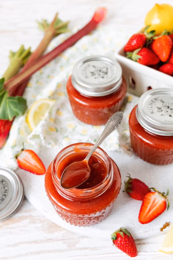 Erdbeer-Rhabarber-Konfitüre in einem Glas mit Löffel.