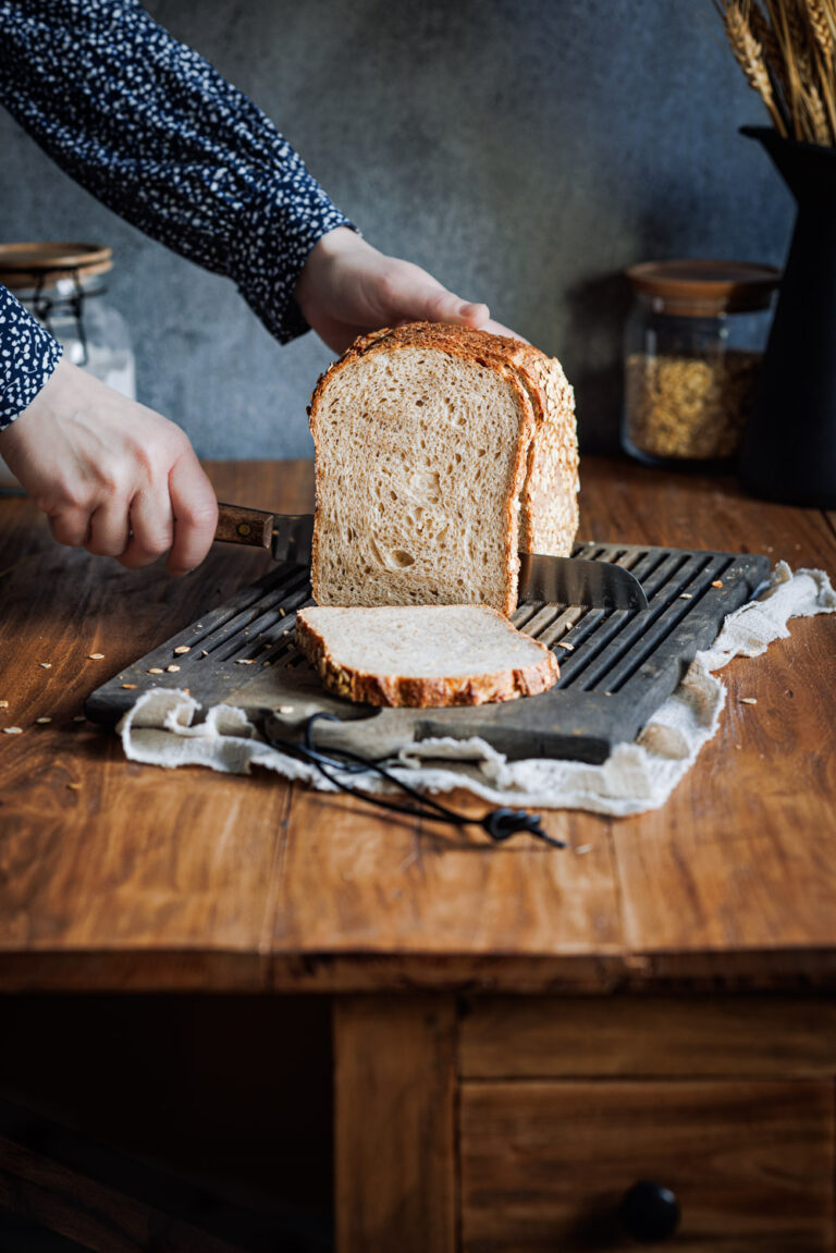 Hafer-Joghurt-Brot auf einem Holzbrett, das in Scheiben geschnitten wird.