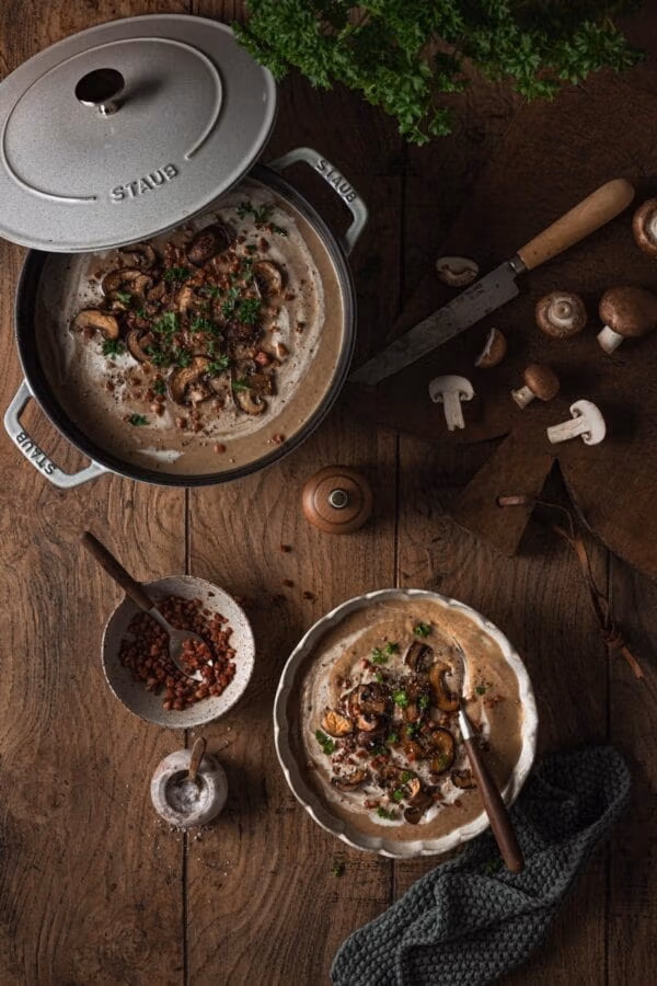 Pilzrahmsuppe mit gebratenen Champignons, Speck und Petersilie.