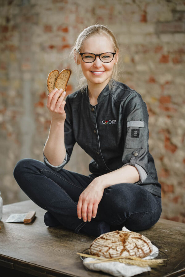 Sonja Bauer mit Brot in der Hand auf einem Holztisch.