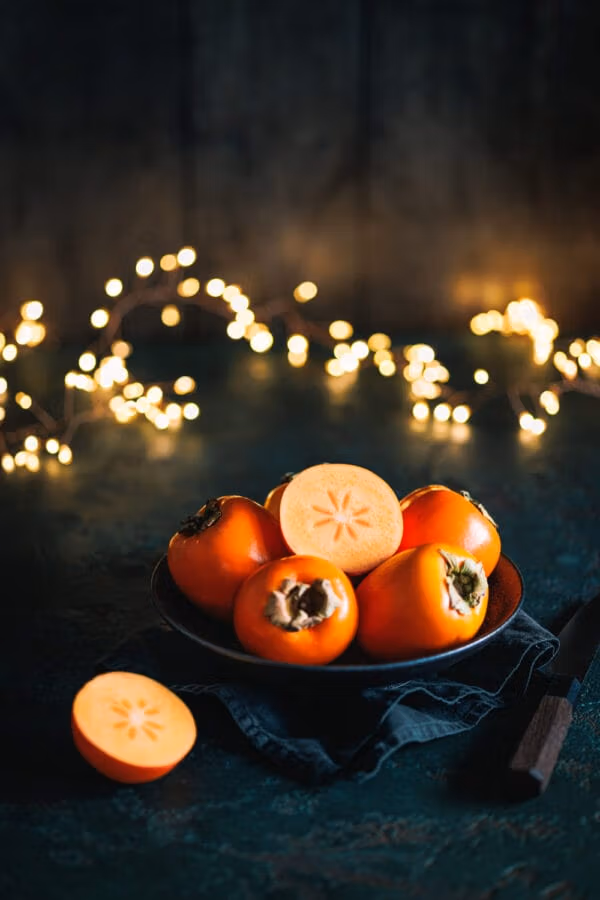 Kakis n eine Schale mit einer Lichterkette im Hintergrund. 