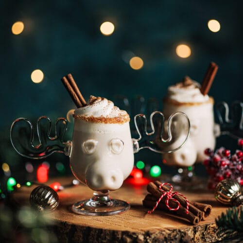 Alkoholfreier Eierpunsch in einer Elchtasse mit Sahnehaube und Zimtstange in einem weihnachtlichen Setting.