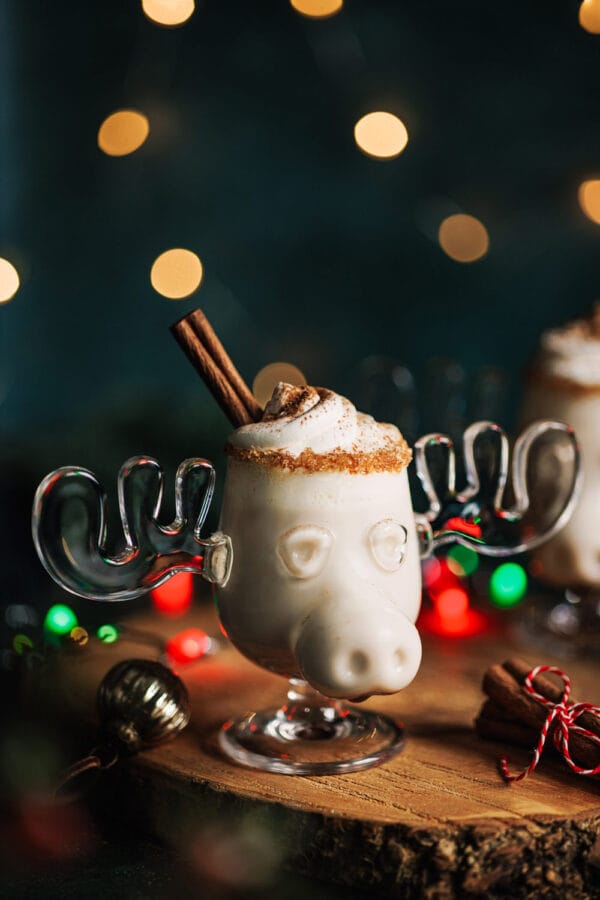 Alkoholfreier Eierpunsch in einer Elchtasse mit Sahnehaube und Zimtstange in einem weihnachtlichen Setting. 