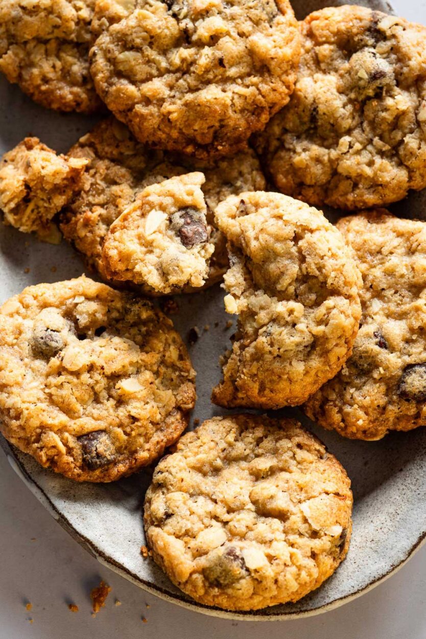 Nahaufnahme von goldbraun gebackenen schwedischen Hafercookies mit Sauerteig, gefüllt mit Schokoladenstückchen und Nüssen, serviert auf einer rustikalen Platte.