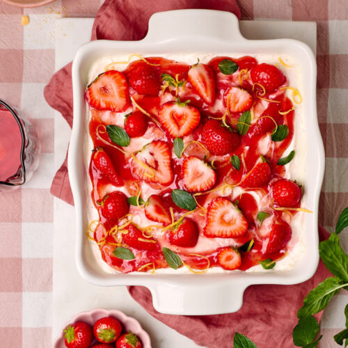 Erdbeer-Tiramisu in einer Keramikform mit dem Löffelbiskuit und Erdbeeren daneben.