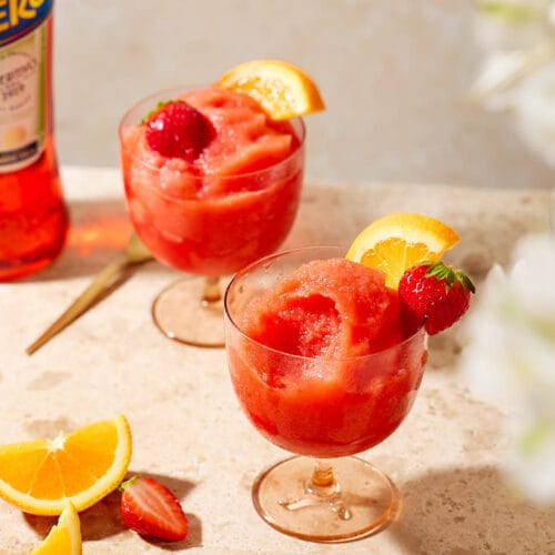 Fruchtiges Sorbet aus Aperol, Erdbeeren und Orangensaft in eleganten Gläsern mit frischer Deko.