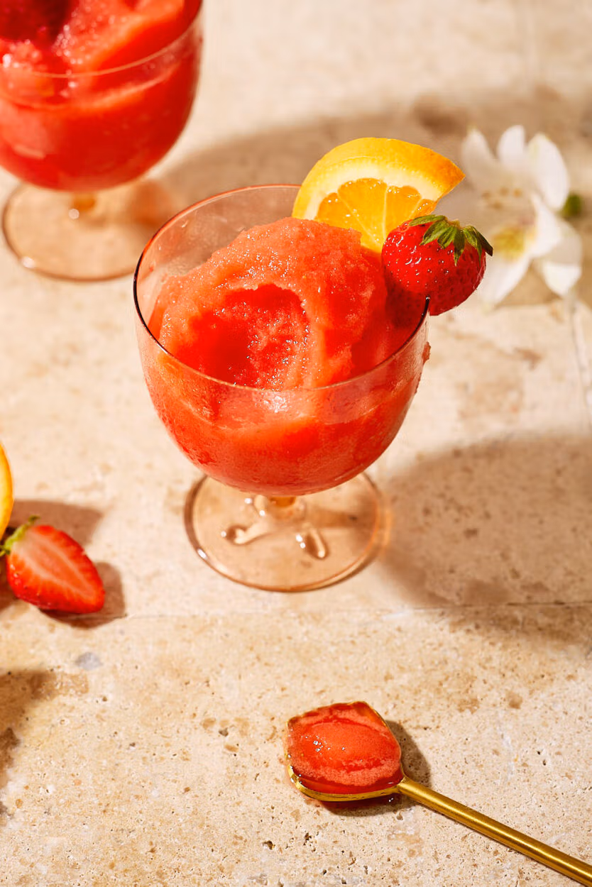 Nahaufnahme eines Glases mit Frozen Aperol Spritz, Eisstruktur und Früchten im Fokus.