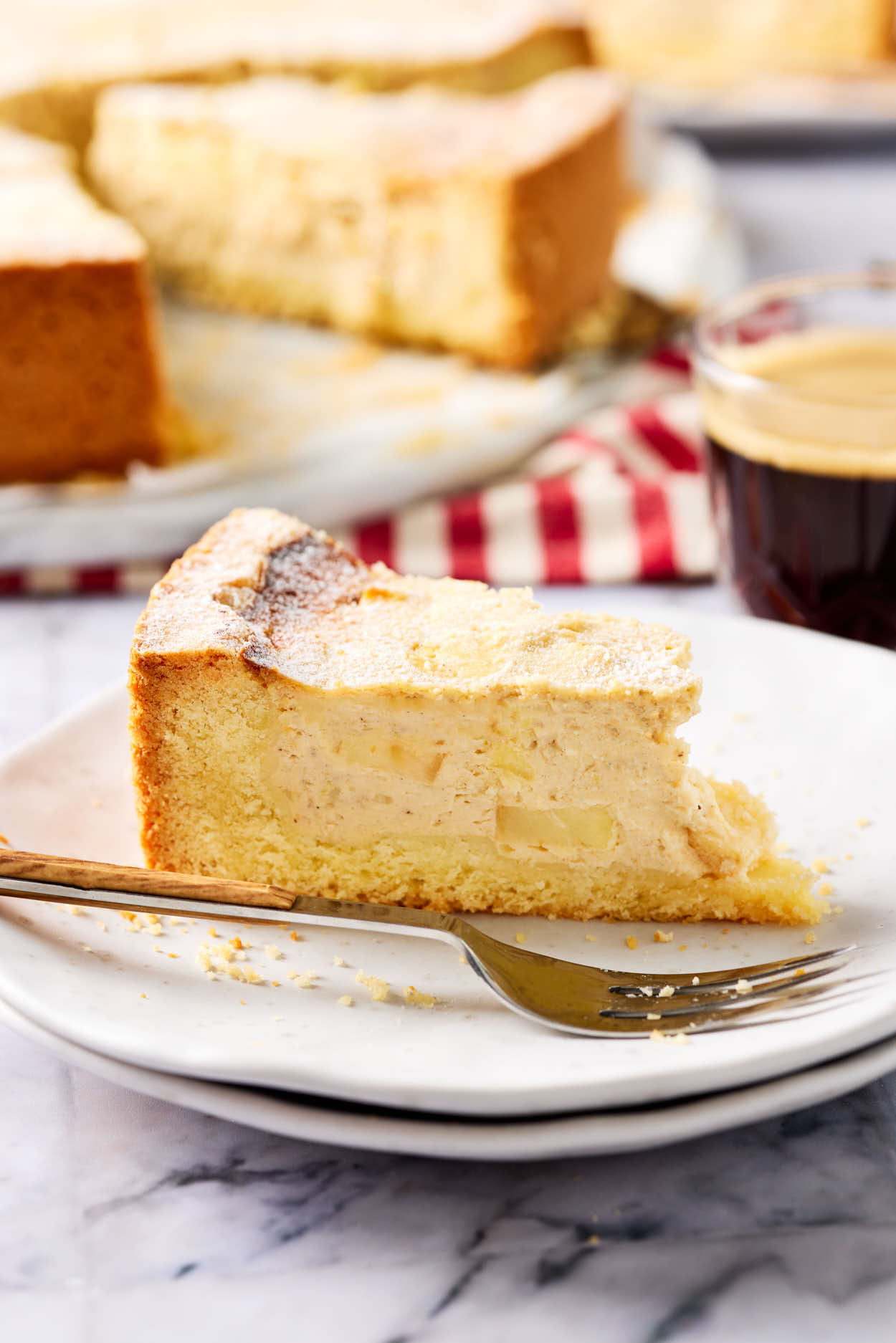Ein Stück saftiger Apfel-Quark-Kuchen mit zartem Mürbeteigboden auf einem Kuchenteller, mit einer Gabel.