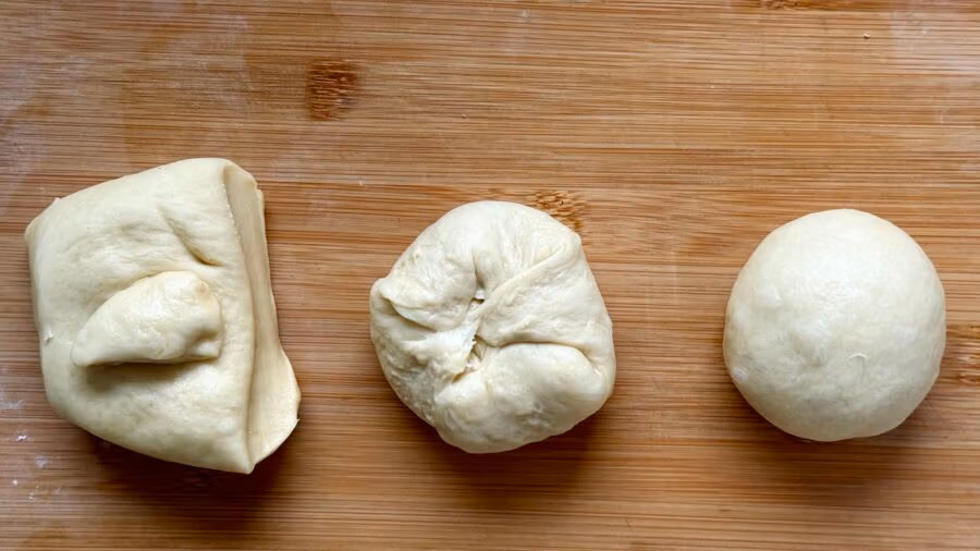 Teiglinge für Brioche Buns in drei Stadien des Formens: abgewogen, rundgewirkt und rundgeschliffen.