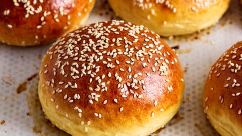 Mehrere Brioche Burger Buns auf einem mit Backpapier belegten Backblech, goldbraun gebacken.