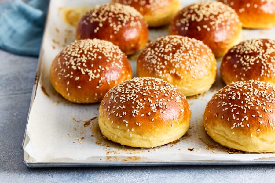 Frisch gebackene Burger Brötchen mit glänzender, goldbrauner Oberfläche auf Backpapier.