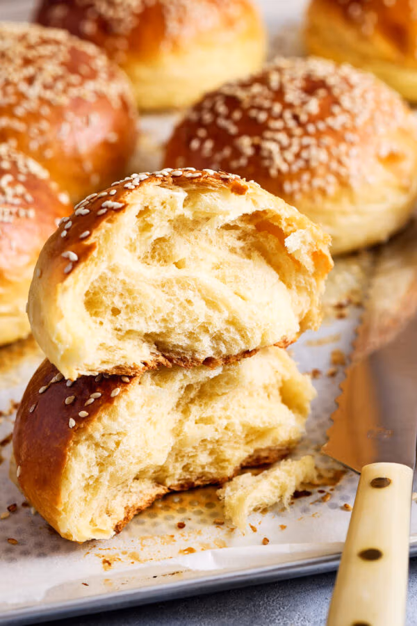 Aufgerissener Brioche Bun auf dem Backblech mit lockerer, weicher Krume.