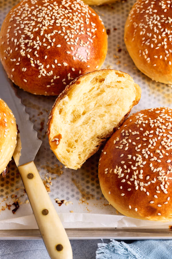 Aufgerissener Brioche Burger Bun auf dem Backblech mit lockerer, weicher Krume.