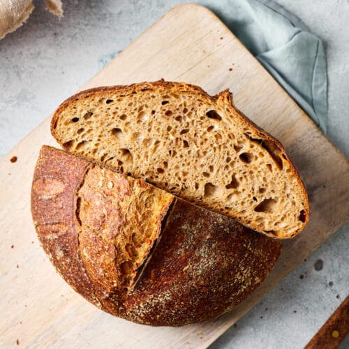 Dinkel-Sauerteigbrot aufgeschnitten auf einem Holzbrett mit sichtbarer lockerer Krume.