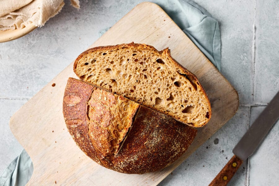 Dinkel-Sauerteigbrot aufgeschnitten auf einem Holzbrett mit sichtbarer lockerer Krume.