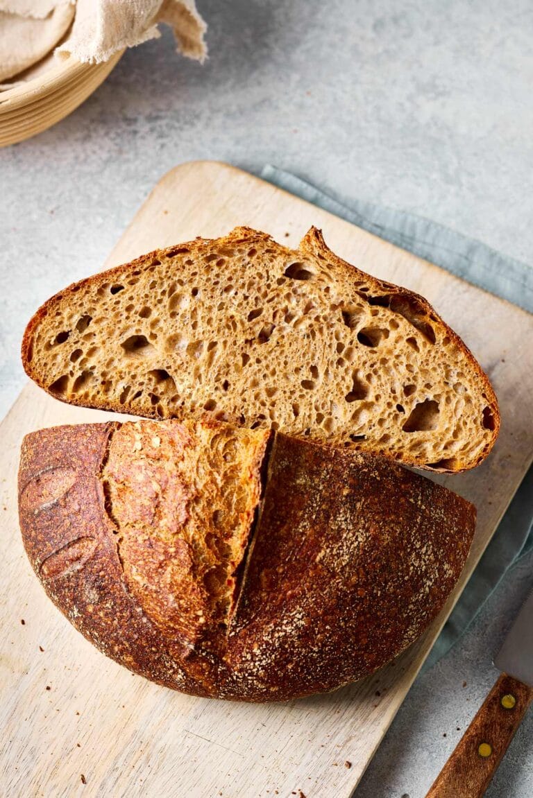Dinkel-Sauerteigbrot aufgeschnitten auf einem Holzbrett mit sichtbarer lockerer Krume.