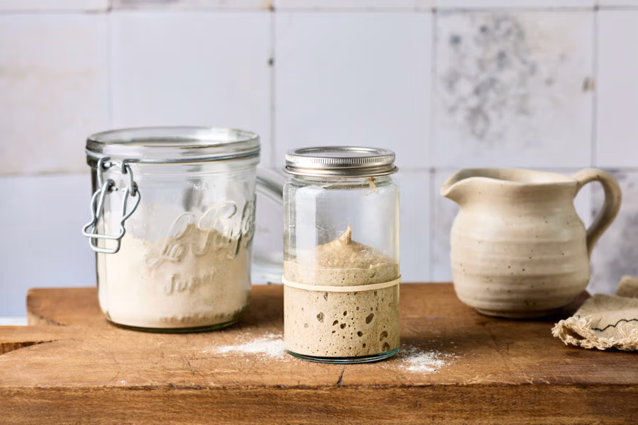 Sauerteig nach dem Füttern in einem Weckglas während der Reifezeit mit sichtbaren Gärbläschen.